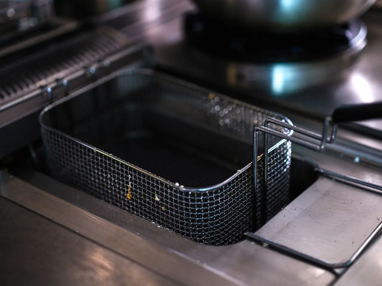 A commercial fryer basket and burner on a shared kitchen cooking station